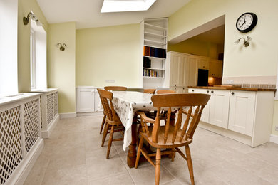 Large modern kitchen/dining room in London with yellow walls and ceramic flooring.