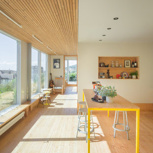 This is an example of a large contemporary kitchen/dining room in London with beige walls, light hardwood flooring and beige floors.