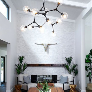 Cette image montre une salle à manger design fermée et de taille moyenne avec un mur blanc, un sol en bois brun, une cheminée double-face, un manteau de cheminée en pierre de parement, un sol marron et un plafond voûté.