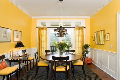 Example of a mid-sized classic dark wood floor enclosed dining room design in Other with yellow walls and no fireplace