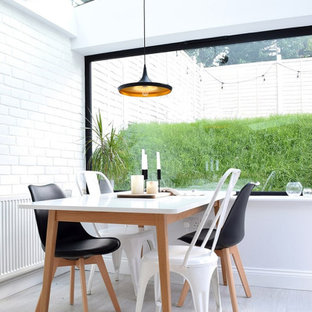 Immagine di una sala da pranzo nordica con pareti bianche, pavimento grigio, soffitto a volta e pareti in mattoni