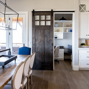 Immagine di una grande sala da pranzo aperta verso il soggiorno country con pavimento in legno massello medio, pareti gialle e nessun camino
