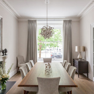 Photo of a classic enclosed dining room in London with beige walls, medium hardwood flooring, a standard fireplace and brown floors.