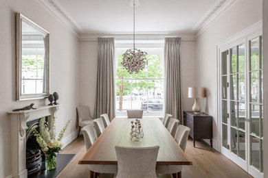 Photo of a classic enclosed dining room in London with beige walls, medium hardwood flooring, a standard fireplace and brown floors.