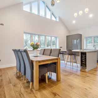 Design ideas for a medium sized contemporary open plan dining room in Dorset with white walls, medium hardwood flooring, no fireplace and brown floors.