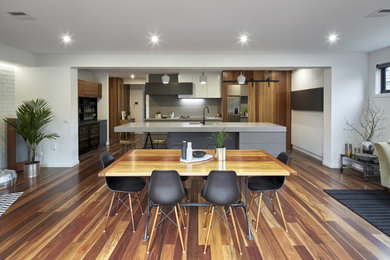 Diseño de comedor de tamaño medio abierto con paredes blancas, suelo de madera en tonos medios y suelo marrón