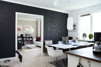 Cette image montre une salle à manger ouverte sur la cuisine design de taille moyenne avec un mur noir et parquet clair.