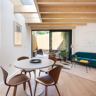 This is an example of a medium sized contemporary dining room in London with white walls, medium hardwood flooring and brown floors.