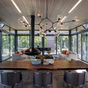 Inspiration pour une salle à manger ouverte sur le salon design avec béton au sol et cheminée suspendue.