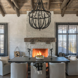Photo of a country dining room in Other with white walls, medium hardwood floors, a standard fireplace, brown floor and a stone fireplace surround.