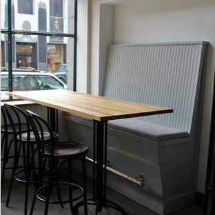 Idee per una sala da pranzo aperta verso il soggiorno industriale di medie dimensioni con pareti bianche, parquet scuro, camino sospeso e pavimento nero