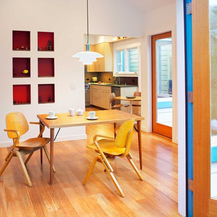 Idée de décoration pour une salle à manger design fermée et de taille moyenne avec un mur blanc, un sol en bois brun et aucune cheminée.