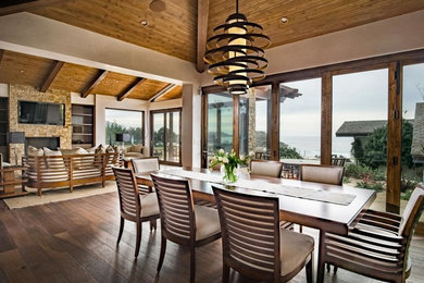 Kitchen/dining room combo - large coastal medium tone wood floor kitchen/dining room combo idea in San Francisco with white walls, a standard fireplace and a stone fireplace