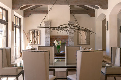 Cette photo montre une salle à manger ouverte sur le salon chic de taille moyenne avec un mur beige, un sol en bois brun, une cheminée standard et un manteau de cheminée en pierre.