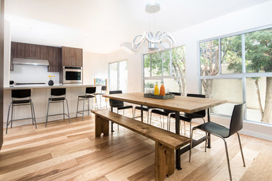 Große Moderne Wohnküche ohne Kamin mit weißer Wandfarbe, braunem Holzboden und braunem Boden in Los Angeles