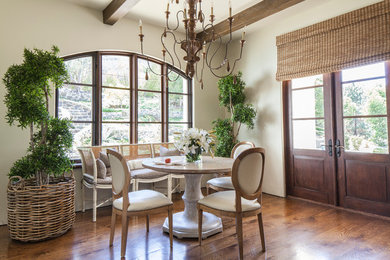 Inspiration pour une salle à manger ouverte sur le salon traditionnelle de taille moyenne avec un mur blanc, un sol en bois brun, aucune cheminée et un sol marron.