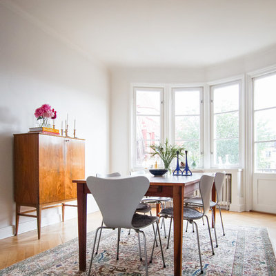 Example of a mid-sized danish medium tone wood floor dining room design in San Francisco with white walls