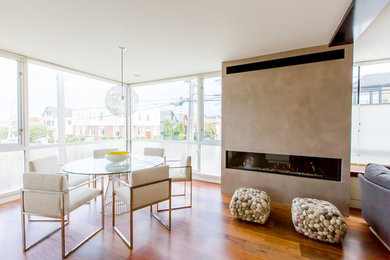 Photo of a contemporary dining room in San Francisco with beige walls, medium hardwood flooring and a ribbon fireplace.