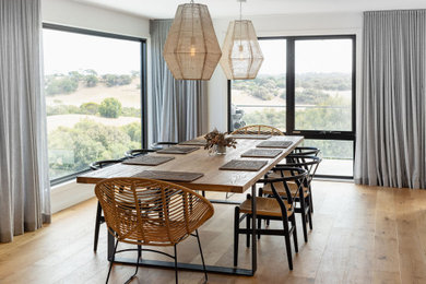 Diseño de comedor actual con paredes blancas, suelo de madera en tonos medios y suelo marrón