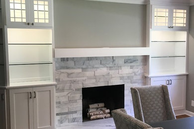 Example of a mid-sized transitional light wood floor and brown floor enclosed dining room design in Cleveland with gray walls, a standard fireplace and a stone fireplace