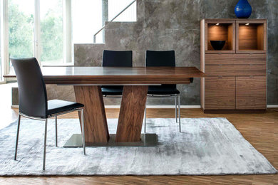 Imagen de comedor contemporáneo de tamaño medio abierto sin chimenea con paredes grises, suelo de madera en tonos medios y suelo marrón