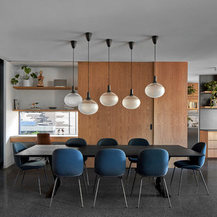 Inspiration pour une salle à manger design avec béton au sol, une cheminée d'angle, un manteau de cheminée en béton et un sol noir.