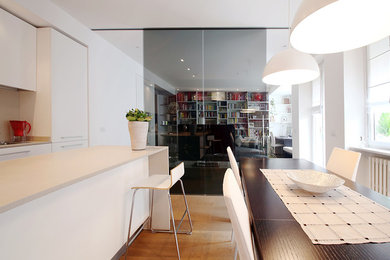 Immagine di una sala da pranzo aperta verso la cucina contemporanea di medie dimensioni con pareti bianche e pavimento in legno massello medio