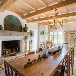 Réalisation d'une grand salle à manger méditerranéenne avec un mur blanc, un sol en carreau de terre cuite, une cheminée standard et un manteau de cheminée en pierre.