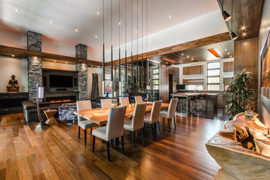 Aménagement d'une salle à manger ouverte sur le salon contemporaine avec un mur blanc, un sol en bois brun et une cheminée ribbon.