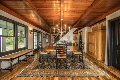 Immagine di una grande sala da pranzo aperta verso la cucina rustica con pareti bianche, pavimento in legno massello medio, nessun camino e pavimento marrone