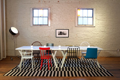 Réalisation d'une salle à manger urbaine avec un mur blanc, un sol en bois brun et éclairage.