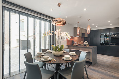 This is an example of a medium sized contemporary kitchen/dining room in London with white walls, light hardwood flooring and brown floors.