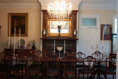 Example of a large classic dark wood floor and brown floor enclosed dining room design in Other with yellow walls and a standard fireplace