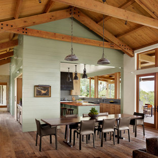 Immagine di un'ampia sala da pranzo aperta verso il soggiorno country con pavimento marrone, pareti verdi, parquet scuro, travi a vista, soffitto a volta, soffitto in legno e pareti in perlinato