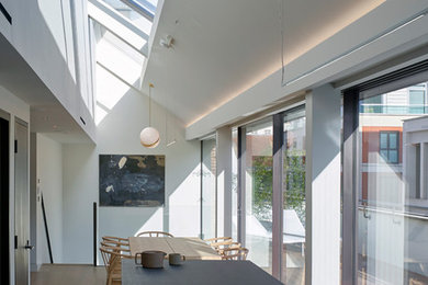 Esempio di una grande sala da pranzo aperta verso il soggiorno design con pareti grigie e parquet chiaro