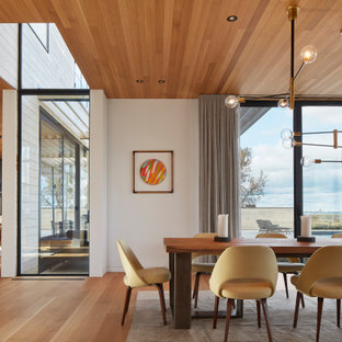 Aménagement d'une salle à manger ouverte sur le salon contemporaine avec un mur blanc, un sol en bois brun, aucune cheminée, un sol marron et un plafond en bois.