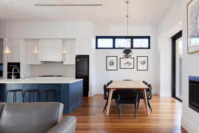 Aménagement d'une salle à manger ouverte sur le salon classique de taille moyenne avec un mur blanc et un sol en bois brun.