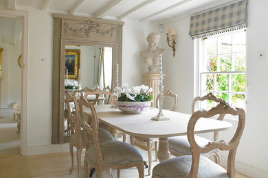 Imagen de comedor romántico cerrado sin chimenea con paredes blancas y suelo de madera clara