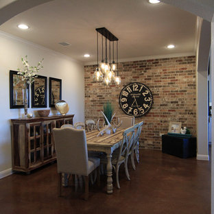 Idee per una sala da pranzo aperta verso la cucina tradizionale di medie dimensioni con pareti beige, pavimento in cemento, camino ad angolo e cornice del camino in mattoni
