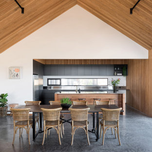 Cette image montre une salle à manger ouverte sur le salon rustique en bois avec un mur blanc, béton au sol, un sol gris, un plafond voûté et un plafond en bois.