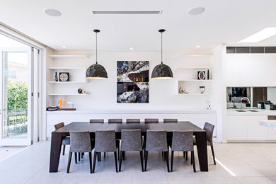 Contemporary kitchen/dining room in Sydney with white walls, beige floors and feature lighting.