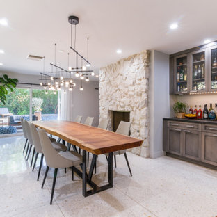 Foto de comedor de cocina clásico renovado, grande, con paredes grises, suelo de madera en tonos medios, chimeneas suspendidas, marco de chimenea de piedra y suelo marrón