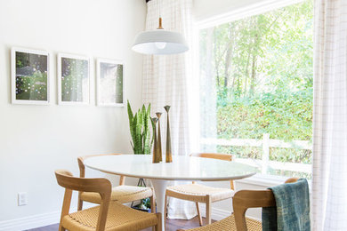 Réalisation d'une petite salle à manger ouverte sur la cuisine bohème avec un mur blanc, un sol en bois brun et un sol marron.