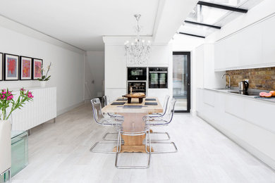 Immagine di una sala da pranzo aperta verso la cucina design con pareti bianche e pavimento in legno verniciato