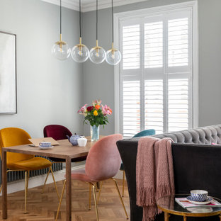 Eclectic dining room in London with grey walls, medium hardwood flooring and brown floors.
