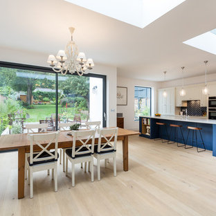 Photo of a large contemporary kitchen/dining room in London with white walls and light hardwood flooring.