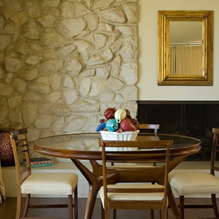 Diseño de comedor clásico renovado con paredes beige, suelo de madera oscura, marco de chimenea de piedra y chimenea lineal