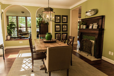 Immagine di una grande sala da pranzo aperta verso il soggiorno tradizionale con pareti verdi, parquet scuro e camino classico