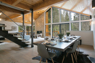 Diseño de comedor moderno de tamaño medio abierto con paredes blancas, suelo de madera en tonos medios y marco de chimenea de metal