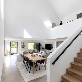 Idee per una piccola sala da pranzo aperta verso la cucina minimalista con pareti bianche, pavimento in cemento, nessun camino, pavimento grigio e soffitto a volta